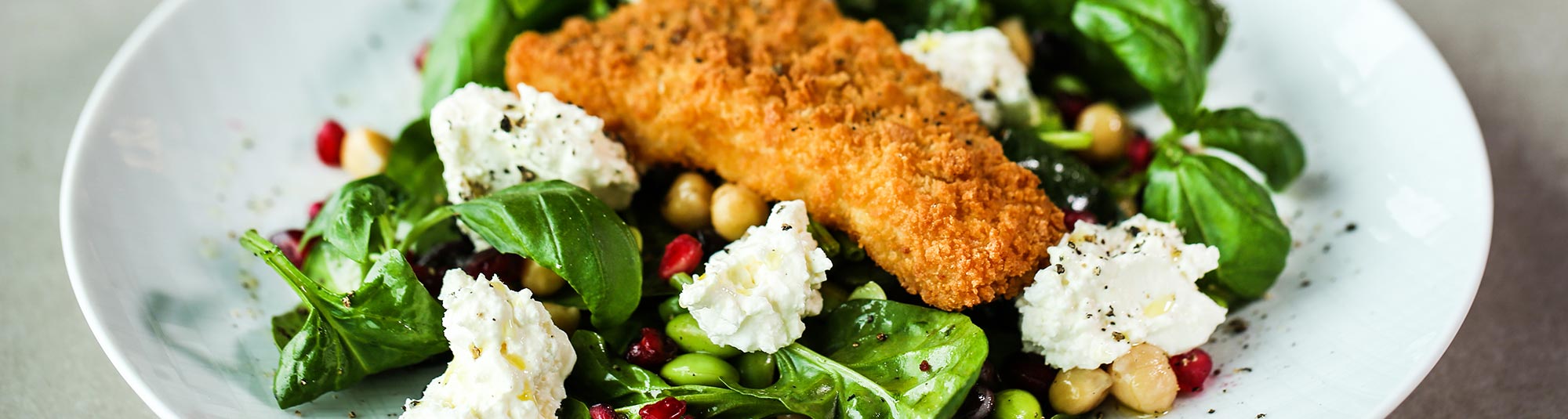 Frasig panerad fiskfilé med sallad och fetaostkräm.