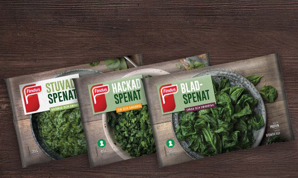 Tre förpackningar av Findus frysta spenat på träbakgrund